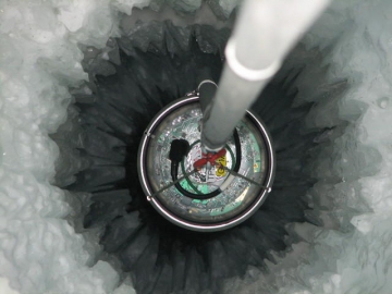 View into the IceCube drill hole, lowering an IceCube module into the ice (Credit: DESY)