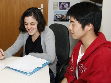 A female and a male DESY-summer student sitting at a table with documents on it
