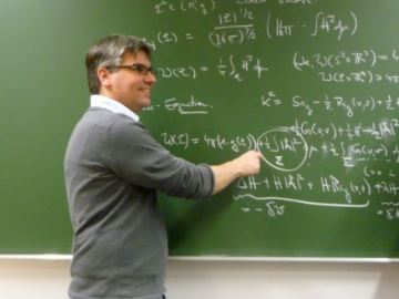 A male scientist from the AEI at a blackboard with mathematical formulas on it