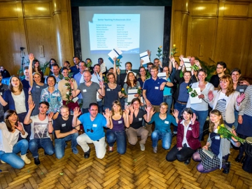 Eine große Gruppe Promovierender der Potsdam Graduate School winkt und hält ihre Zertifikate vom Programm "Teaching Professionals" in die Luft