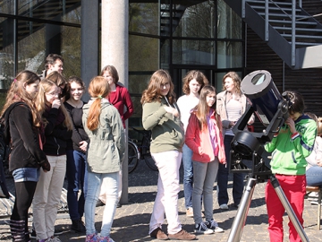 Potsdam: Eine Gruppe von Schülerinnen steht um ein Teleskop, eine Schülerin schaut hindurch